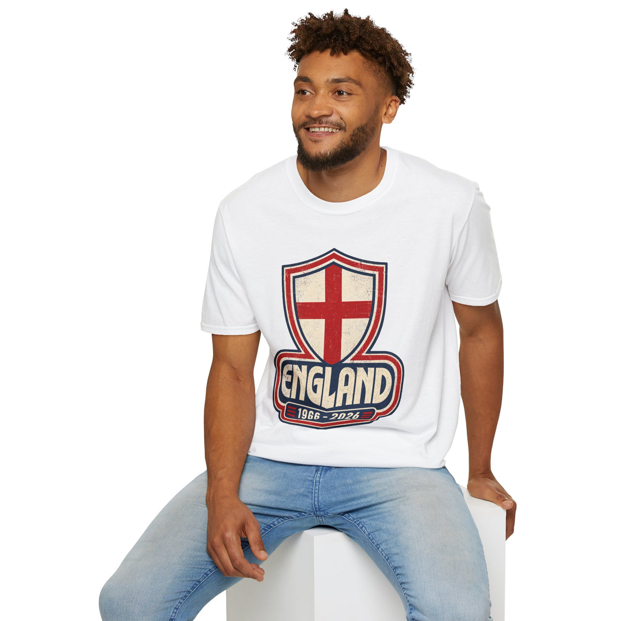 Man wearing a white t-shirt with an England logo sitting on a white stool against a white background