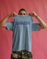 Thumbnail for Person holding up a light blue t-shirt with text against a pink background - Good Morning That’s A Nice TNETENNBA - The IT Crowd T-Shirt