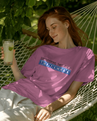 Thumbnail for Person wearing a pink oversized t-shirt with text, sitting in a hammock holding a drink. - Good Morning That’s A Nice TNETENNBA - The IT Crowd T-Shirt