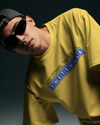 Thumbnail for Person wearing a yellow t-shirt with a blue logo against a dark background - Good Morning That’s A Nice TNETENNBA - The IT Crowd T-Shirt
