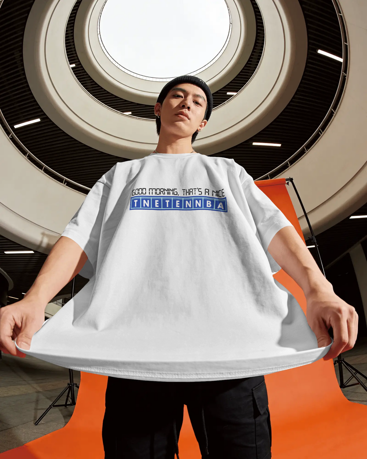 Person holding a large white t-shirt with text in an indoor setting - Good Morning That’s A Nice TNETENNBA - The IT Crowd T-Shirt