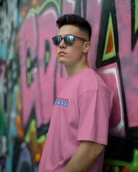 Thumbnail for Person wearing a pink t-shirt with an NBA logo in front of a colourful graffiti wall. - IT Crowd - Tnetennba