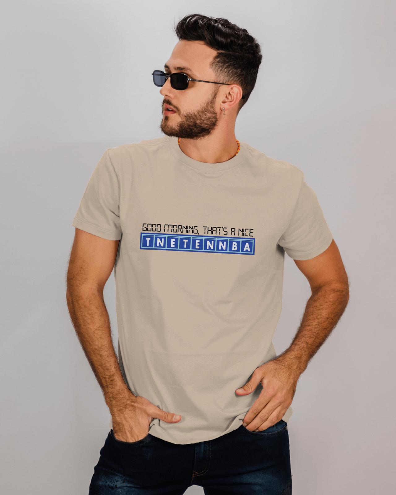 Man wearing a beige t-shirt with text on a plain background - IT Crowd - Tnetennba