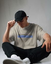 Thumbnail for Person wearing a light gray t-shirt with text and a black cap, sitting on a white floor. - IT Crowd - Tnetennba
