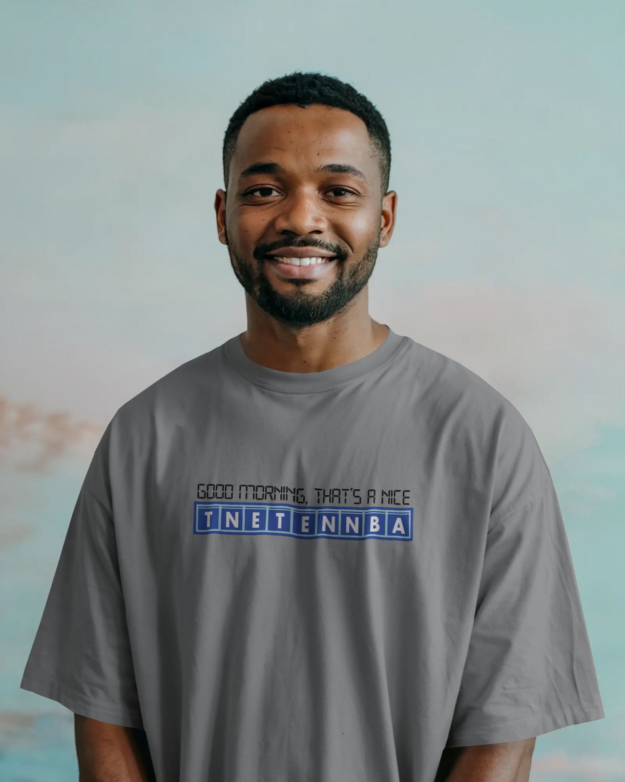 Man wearing a gray t-shirt with text on a blurred background - IT Crowd - Tnetennba