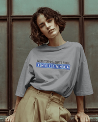 Thumbnail for Person wearing a gray t-shirt with text, sitting against a textured wall. - Good Morning That’s A Nice TNETENNBA - The IT Crowd T-Shirt