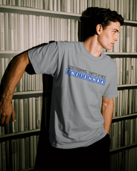 Thumbnail for Person wearing a gray t-shirt with text on the back in front of a bookshelf. - Good Morning That’s A Nice TNETENNBA - The IT Crowd T-Shirt