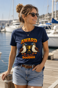 Thumbnail for Woman wearing the Award for the Best Boobies T-Shirt in Navy while relaxing at a marina on a sunny day.