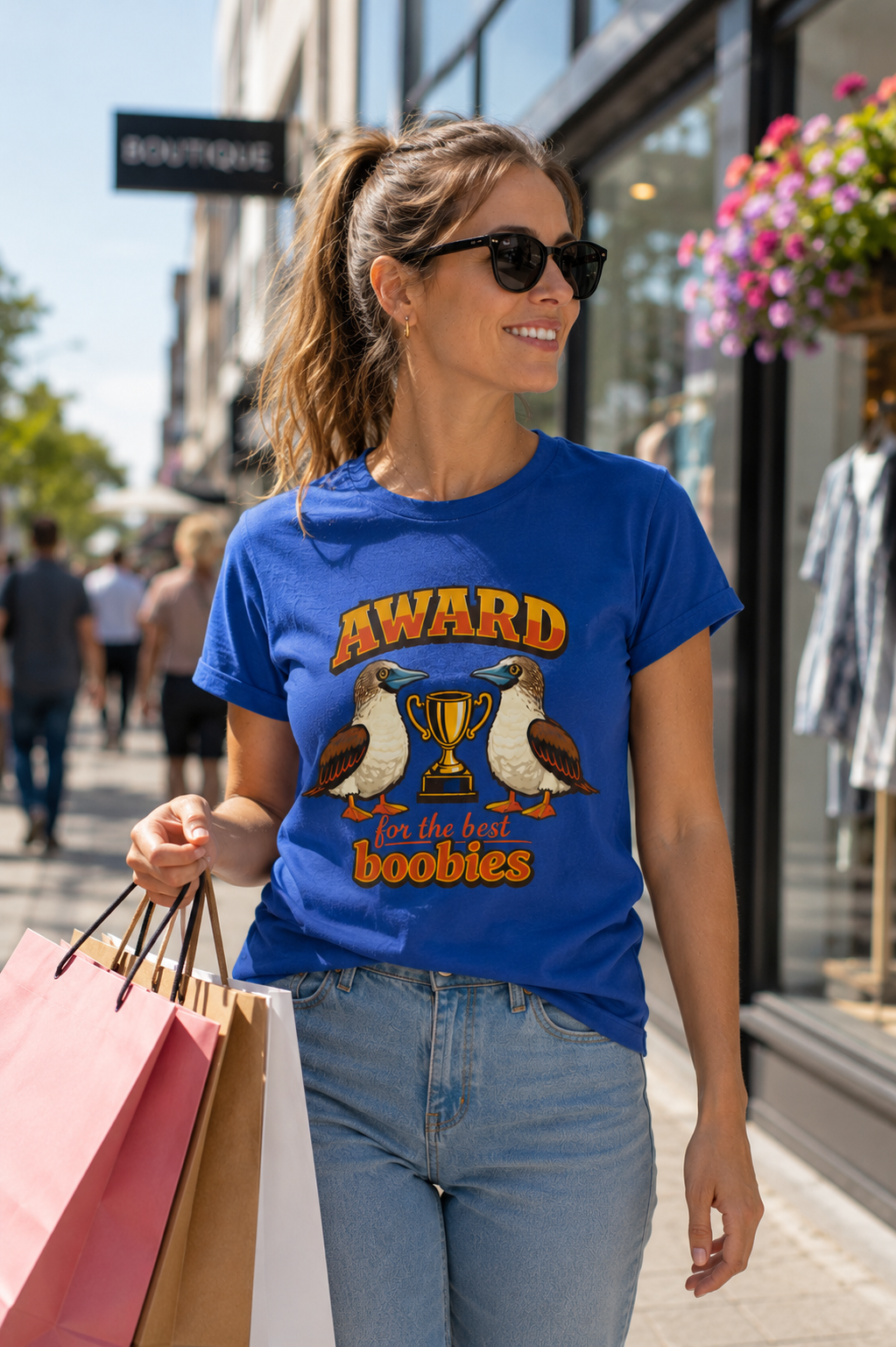 Woman wearing the Award for the Best Boobies T-Shirt in Royal while shopping in a modern city centre.