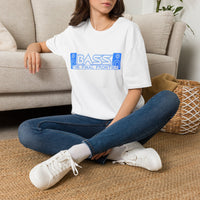 Thumbnail for A woman sitting cross-legged on a woven rug in front of a beige sofa, wearing an oversized white graphic T-shirt with a blue 'BASS' and 'THE FINAL FRONTIER' print, blue jeans, and white sneakers.