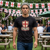 Thumbnail for Man wearing the black England St George Retro T-Shirt in a pub garden with St George flags and football supporters in the background.
