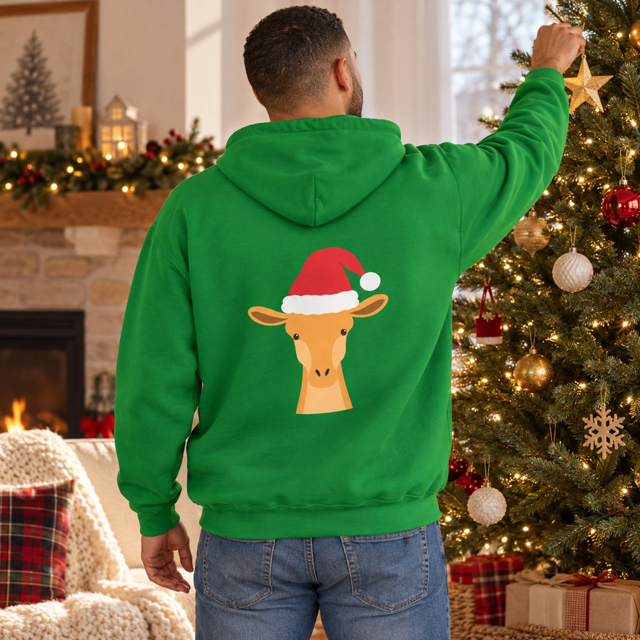 Santa Giraffe Christmas Back Print Hoodie in Irish Green, worn in a Christmas home setting with the Santa giraffe back print visible.