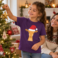 Thumbnail for Santa Giraffe Christmas Kids T-Shirt in Purple, worn in a Christmas home setting with the Santa giraffe front print visible.