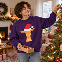 Thumbnail for Santa Giraffe Christmas Sweatshirt in Purple, worn in a Christmas home setting with the Santa giraffe front print visible.