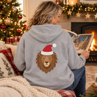 Thumbnail for Santa Lion Christmas Back Print Hoodie in Sport Grey, worn in a Christmas home setting with the Santa lion back print visible.