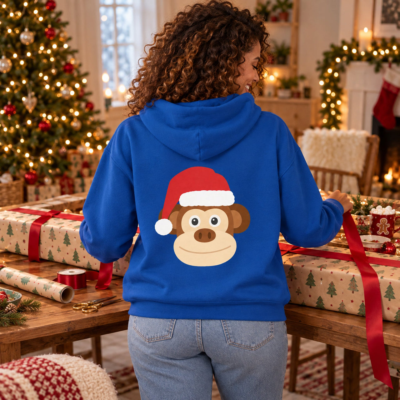 Santa Monkey Christmas Back Print Hoodie in Royal, worn in a Christmas home setting with the Santa monkey back print visible.