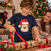 Thumbnail for Santa Monkey Christmas Kids T-Shirt in Navy, worn in a Christmas home setting with the Santa monkey front print visible.
