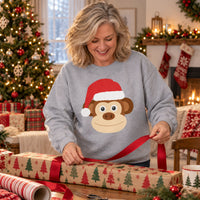 Thumbnail for Santa Monkey Christmas Sweatshirt in Sport Grey, worn in a Christmas home setting with the Santa monkey front print visible.