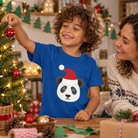 Thumbnail for Santa Panda Christmas kids t shirt in Royal, worn in a festive home setting with the Santa panda front print visible.