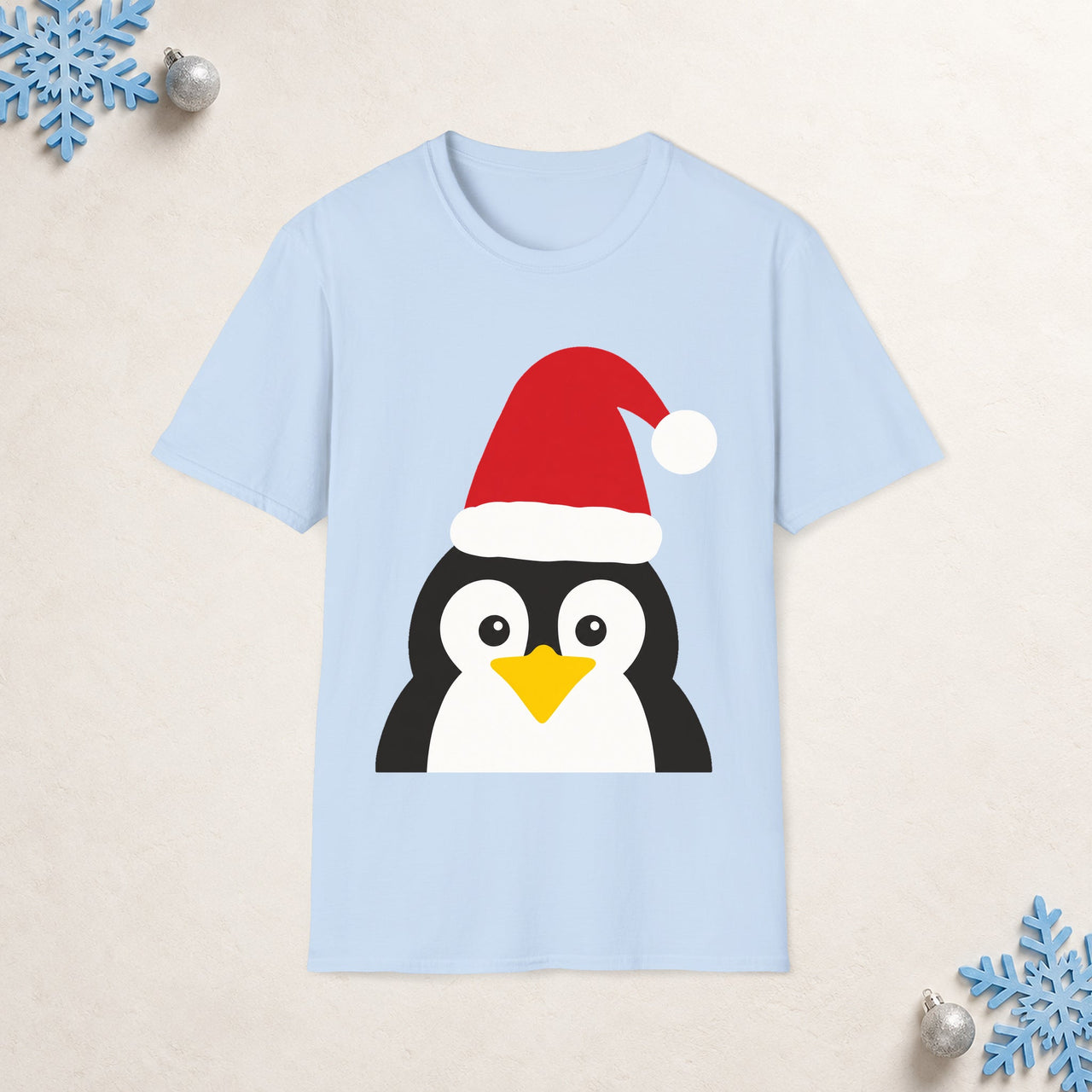 Santa penguin Christmas unisex t shirt in Light Blue, front view with the Santa animal illustration on a Christmas flat-lay background.