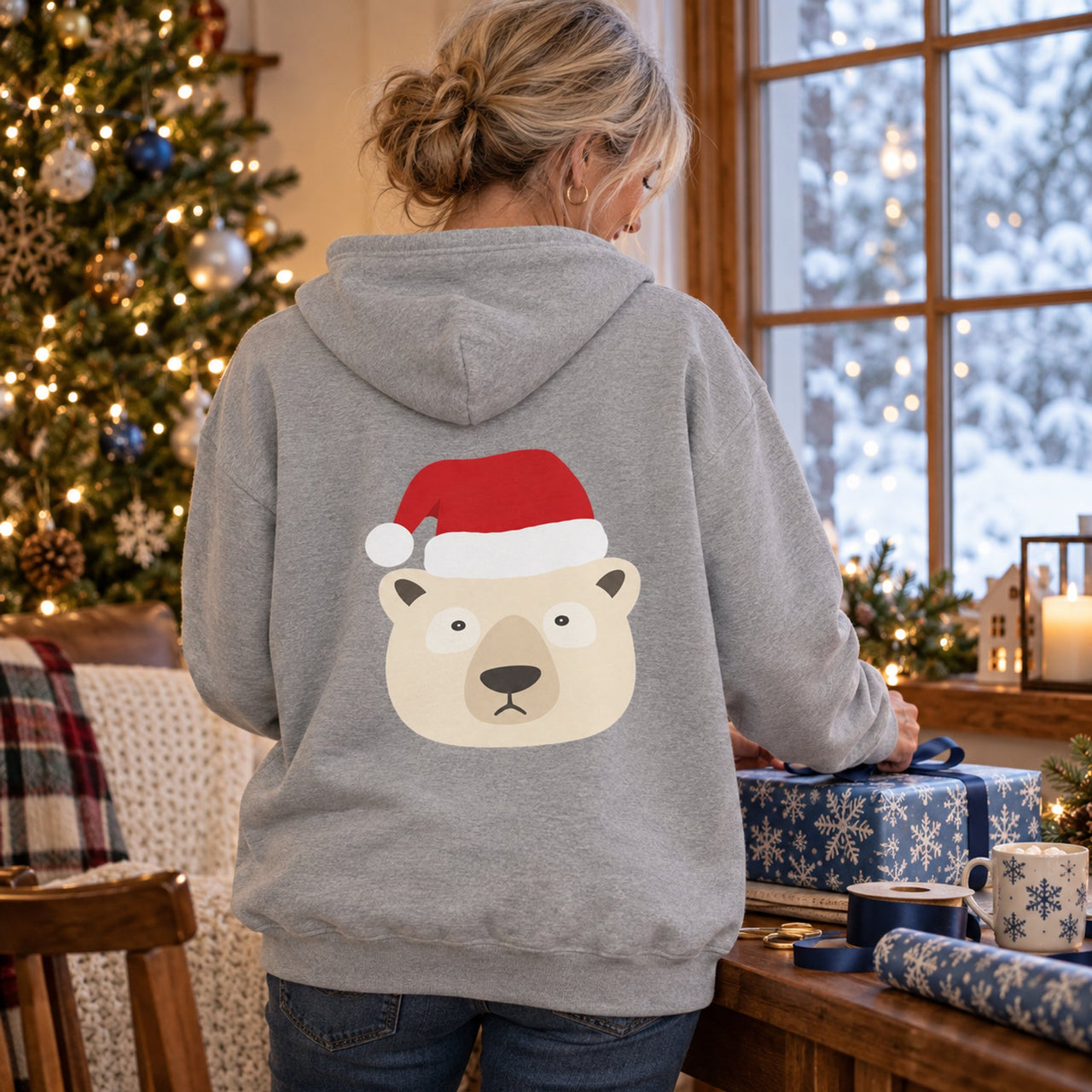 Santa Polar Bear Christmas back print hoodie in Sport Grey, worn in a Christmas home setting with the Santa polar bear back print visible.