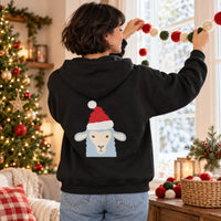 Thumbnail for Santa Sheep Christmas Back Print Hoodie in Black, worn in a Christmas home setting with the Santa sheep back print visible.