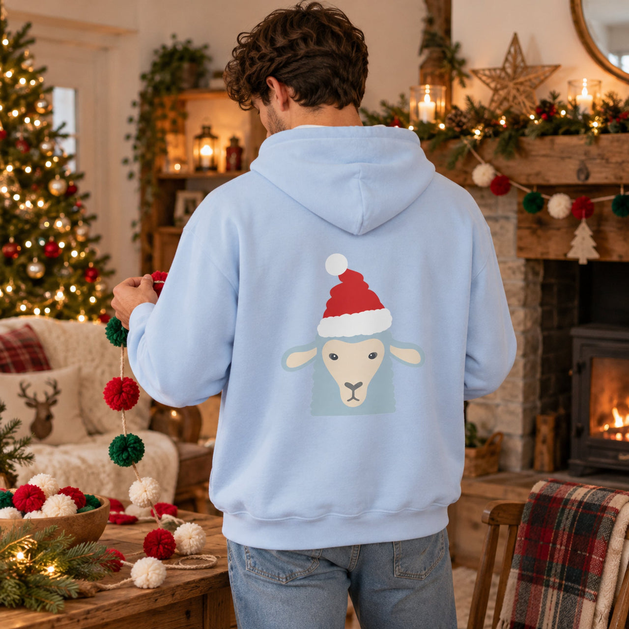 Santa Sheep Christmas Back Print Hoodie in Light Blue, worn in a Christmas home setting with the Santa sheep back print visible.