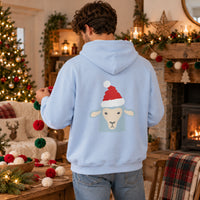 Thumbnail for Santa Sheep Christmas Back Print Hoodie in Light Blue, worn in a Christmas home setting with the Santa sheep back print visible.